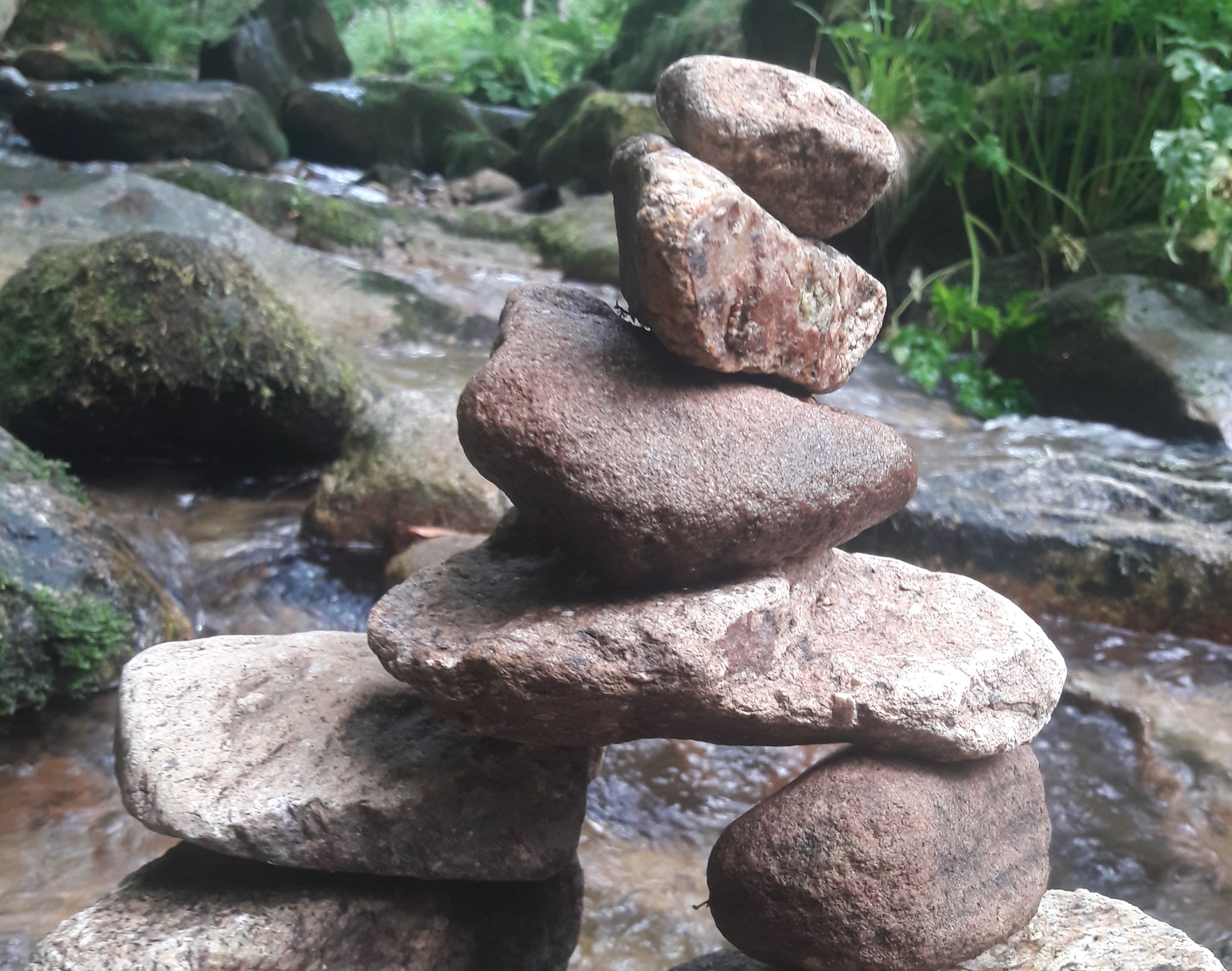 Foto: fragil aufgestapelte mittelgroße Steine über kleinem Flusslauf